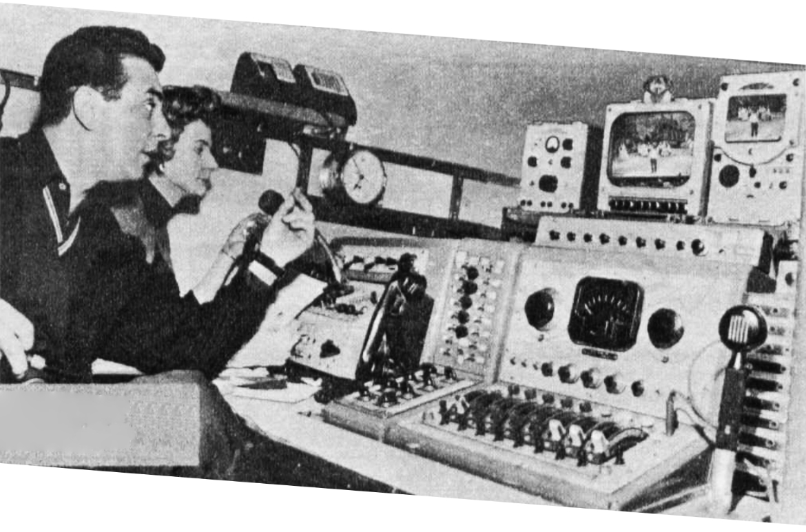 Two people sit at a control desk